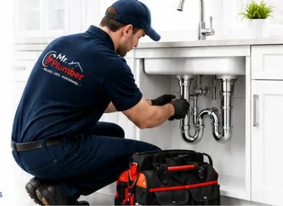 Mr. Plumber technician repairing pipes under a kitchen sink